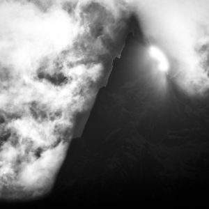 Photo Chamonix aiguille du midi-Dent du Caiman in the Mont Blanc massif, a rocky needle dramatically emerging from the clouds with spectacular contrasts and a spectral atmosphere.