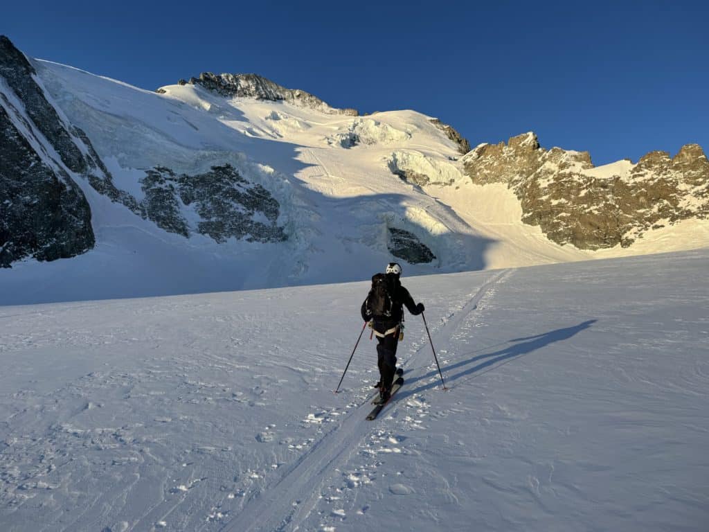 Alpiniste évoluant en direction de la barre des écrins, douce lumière matinale sur les montagnes
