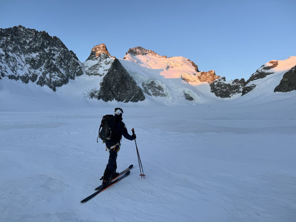 Alpiniste avançant en direction de la barre des écrins, rosé avec le lever de soleil