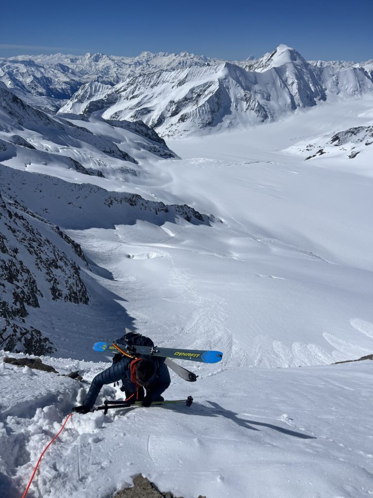 Alpiniste qui remonte la pente de neige du Fieschersattel avec le Aletschhorn et les Alpes valaisannes en arrière plan