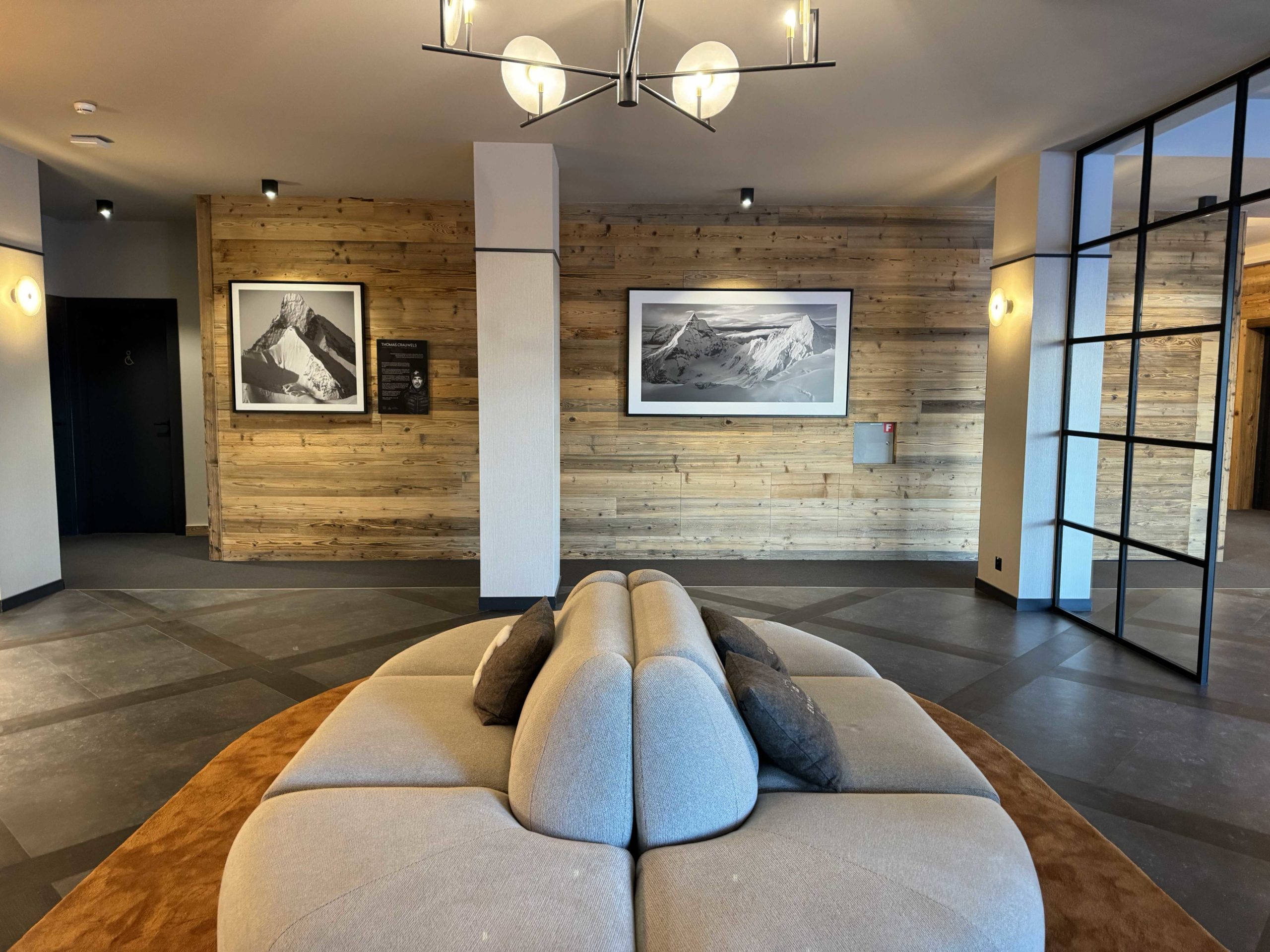 Fotografie des Hotels Eringer mit Sofa im Vordergrund und im Hintergrund des Raumes hängen an der Wand zwei Bergbilder von Thomas Crauwels 