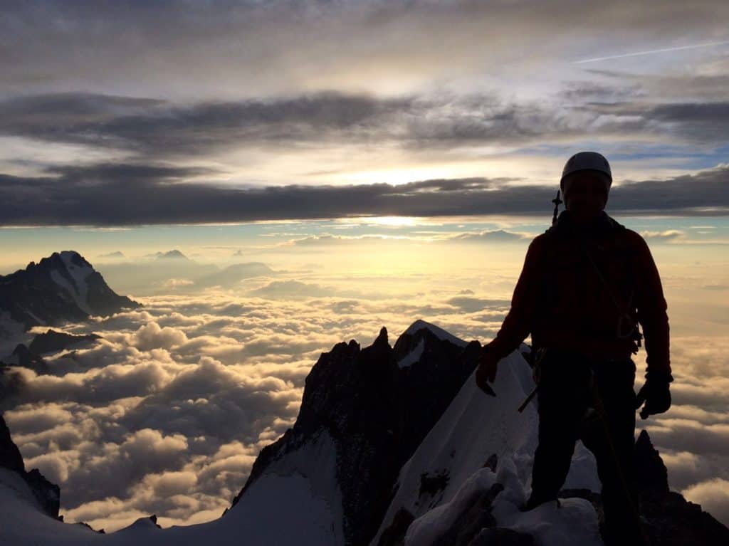 Alpiniste au sommet d'une montagne regardant le lever du soleil