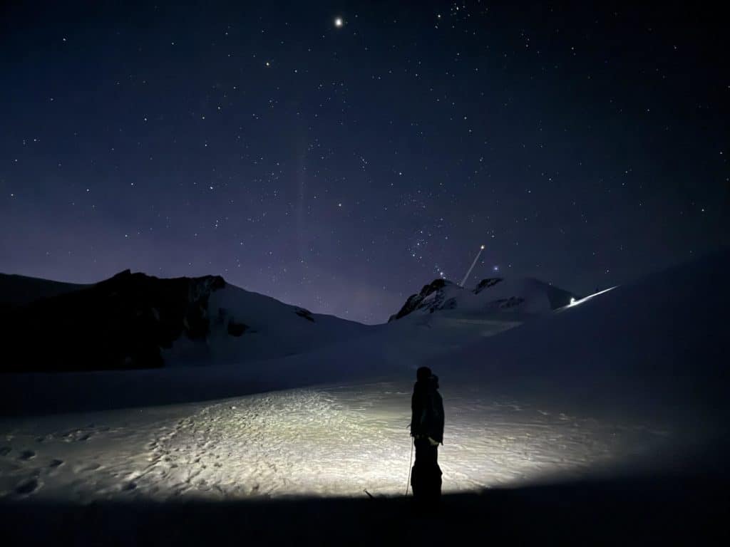 Thomas Crauwels en montagne dans la nuit, sous un ciel étoilé et éclairé par la lumière de la frontale