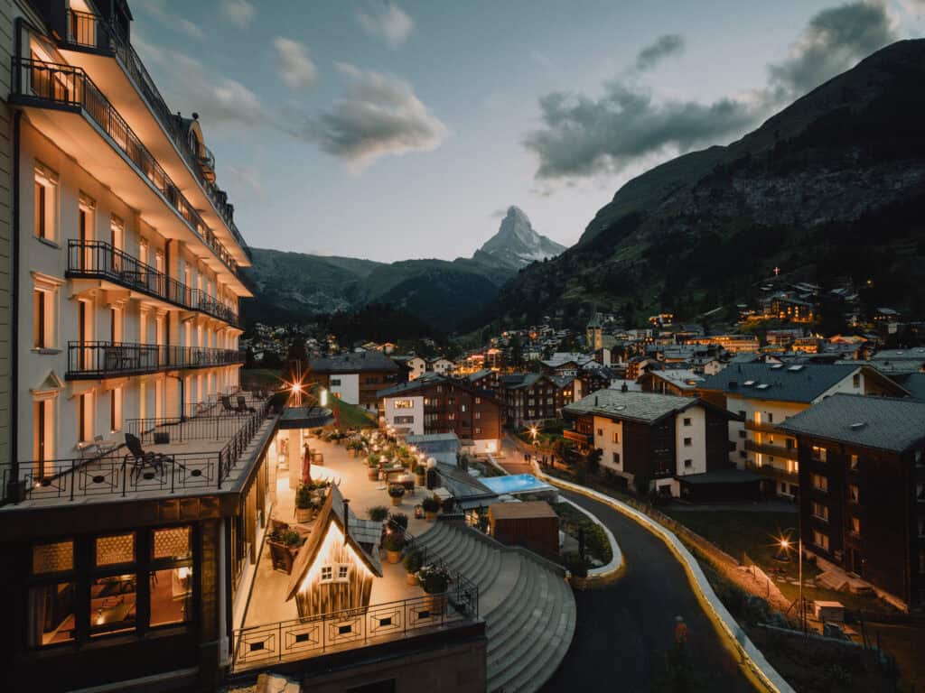 Vue extérieure sur l'hôtel Beausite Zermatt illuminé la nuit avec le Cervin en arrière-plan