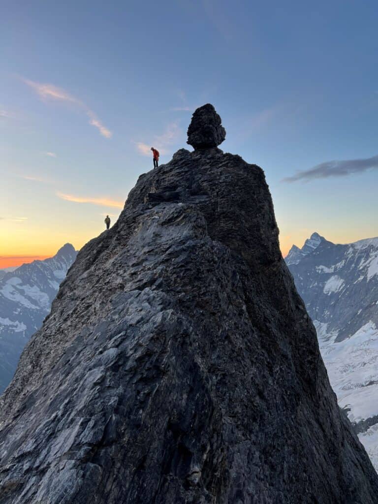 Guide de haute montagne attendant son client au sommet au lever du soleil