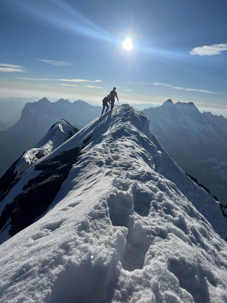 Deux hommes sur le sommet d'une montagne, dont un guide de haute montagne