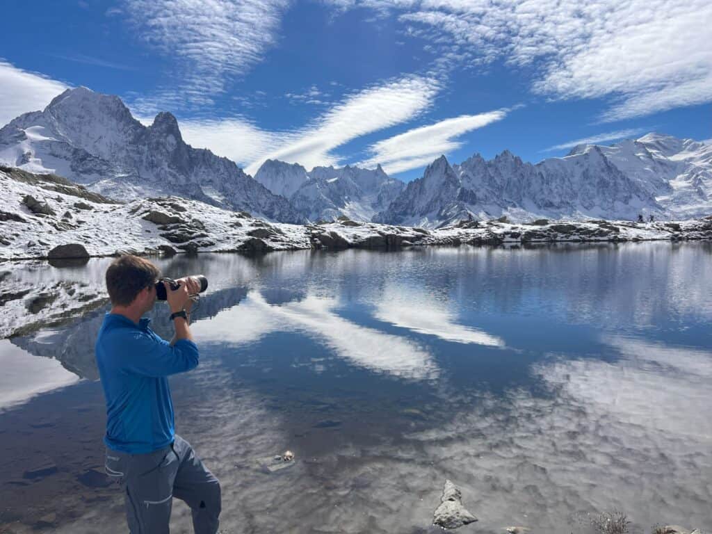 Photographe devant le lac blanc à Chamonix en train de photographier le massif du mont blanc fraichement recouvert de neige