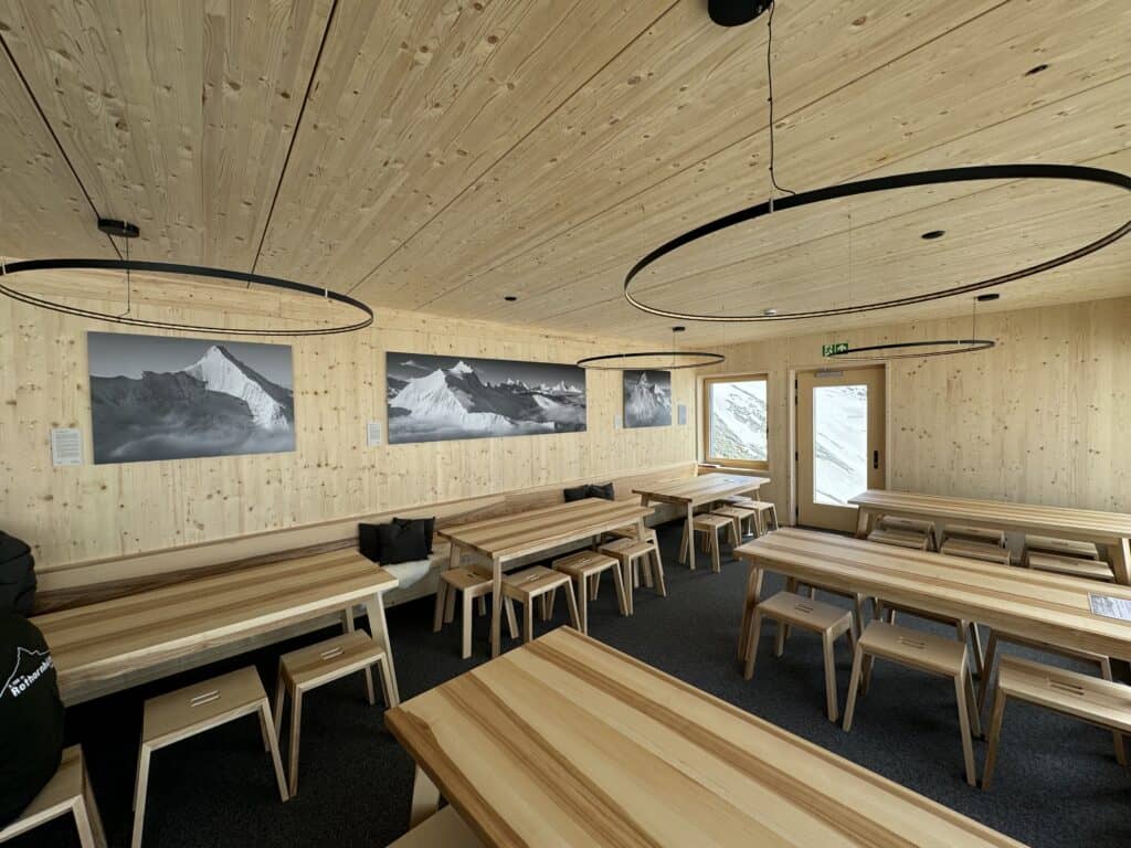 Interior of the ru Rothorn hut with three photographs of Thomas Crauwels hung on the wooden wall