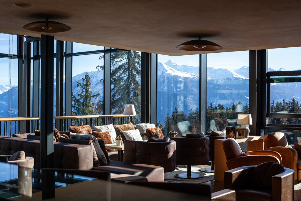 Innenansicht eines Hotels mit Blick auf die Berge von Crans Montana hinter den Fenstern