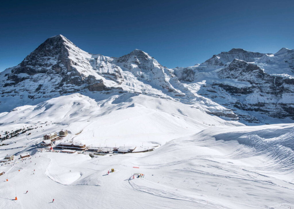 Paysage hivernal de la Kleine Scheidegg à Grindelwald, avec pistes de ski enneigées et vue majestueuse sur l'Eiger, le Mönch et la Jungfrau.