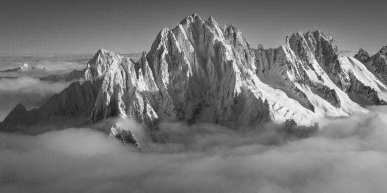 Aiguille Verte et sommets alpins émergeant d'une mer de nuages au lever du soleil en noir et blanc