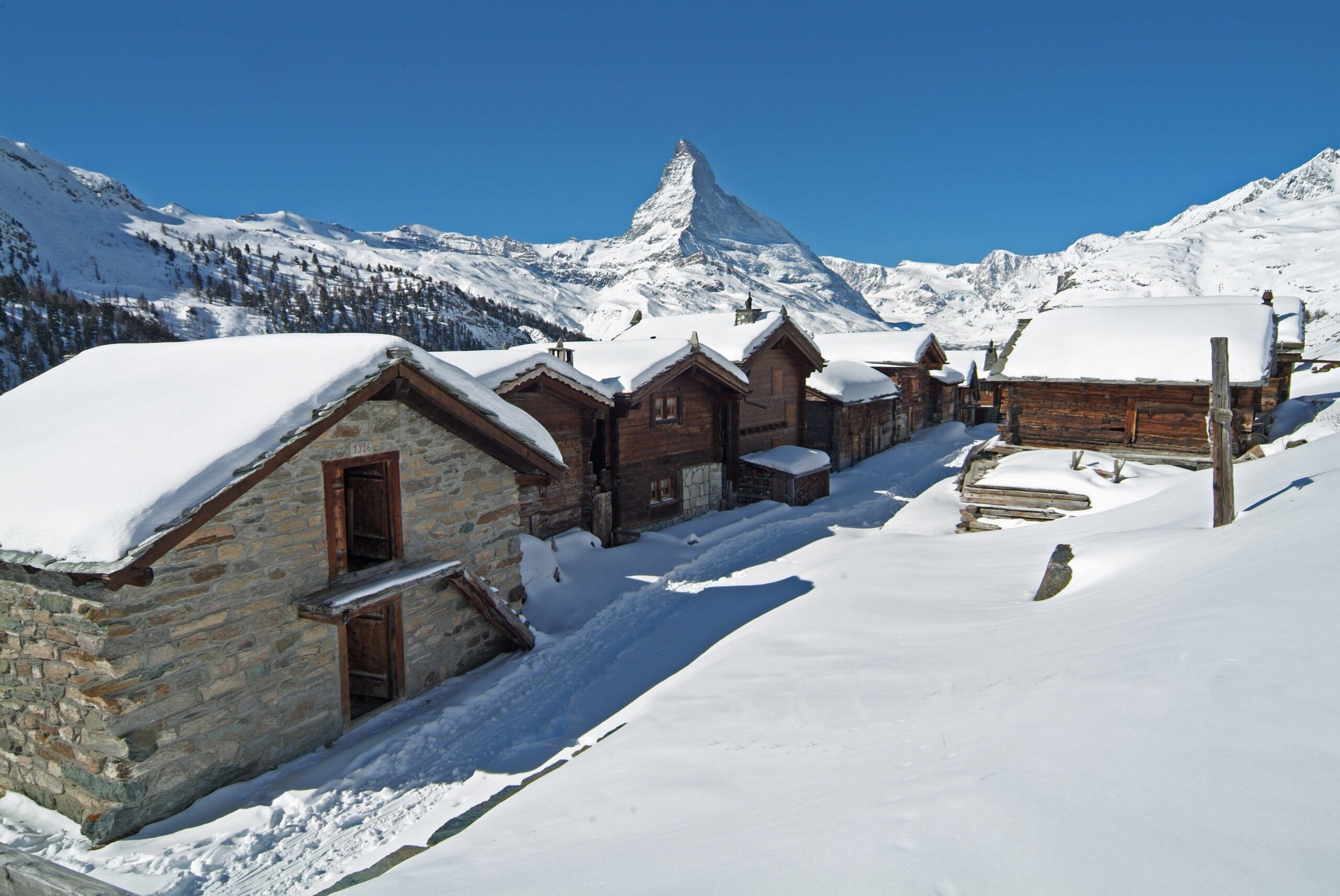 Vue pittoresque du hameau traditionnel de Findeln à Zermatt en hiver, avec ses chalets anciens en bois et pierre enneigés, et le majestueux Cervin en arrière-plan